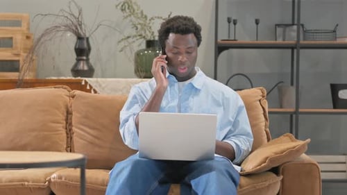 Young Man Working from Home Using Laptop and Phone