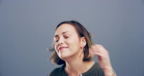 Woman Dancing and Smiling Against Grey Background