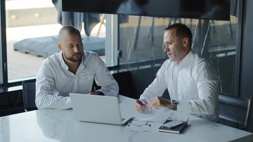 Two Diverse Business Men Discussing Financial Market Data Using Laptop and Digital Tablet