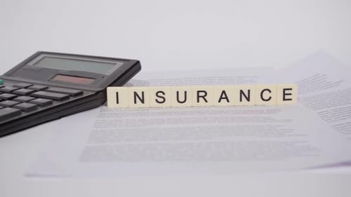 Insurance Spelled Out with Calculator and Paperwork