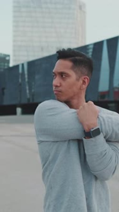 Junger Mann streckt vor dem Training seine Armmuskeln