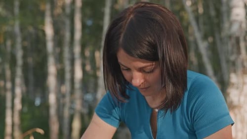 Mujer blanca preparando comida en el campamento con las manos arreglando la comida en un plato, bosque de abedules, telón de fondo cálido