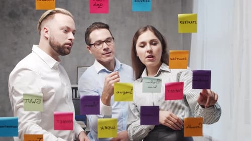 Team of Business People is Doing Brainstorm at a Meeting Using Stickers on the Glass Office Workers