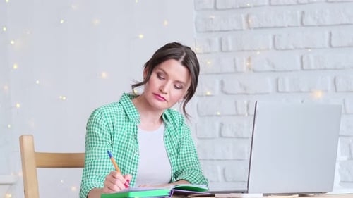 Woman Sitting at a Table Working at a Laptop Computer Concept of Remote Work From Home Home Office