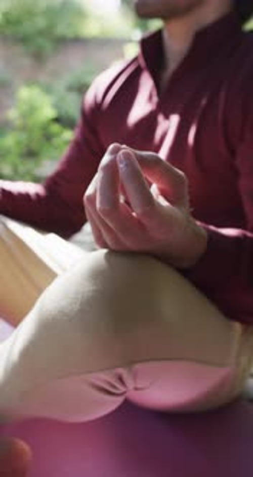 Vertical video of biracial man practicing yoga meditation on terrace in sunny nature, slow motion