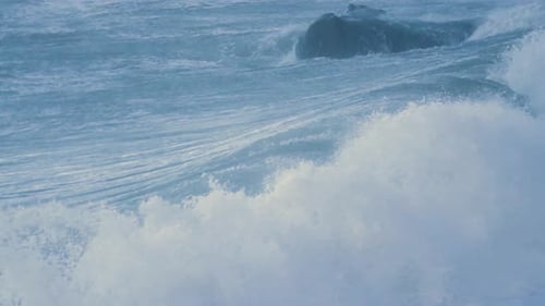 Nahaufnahme großer rauer Meereswellen, die in Zeitlupe auf den Strand prallen