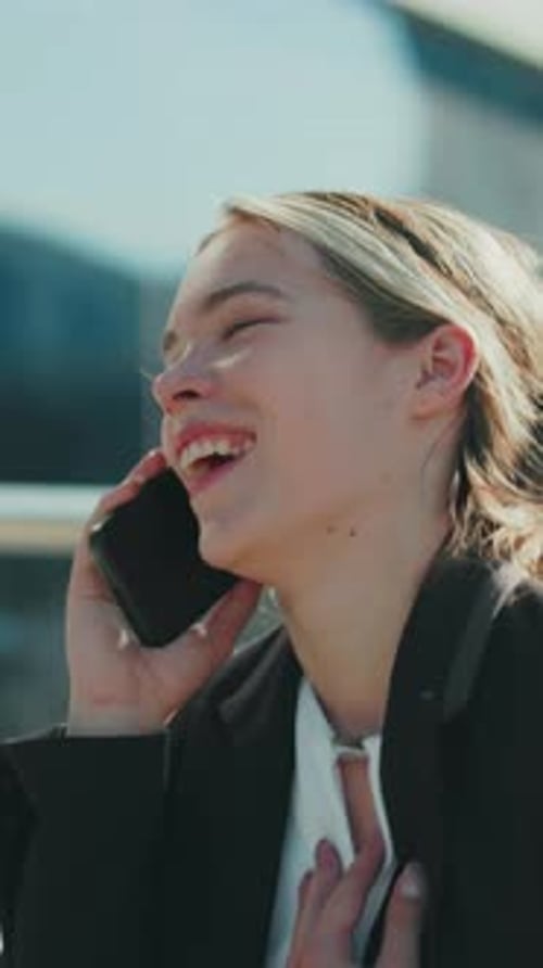 Cheerful Businesswoman Smiling During Phone Call Walking Toward Office Building