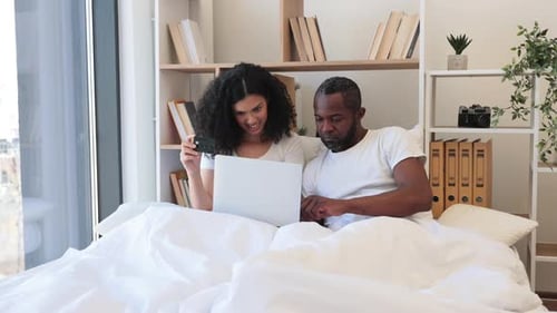 Couple in Bed Shopping Online With Laptop