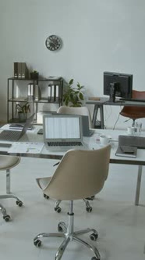 Vertical of Interior of Modern Office with Documents and Open Laptops on Table