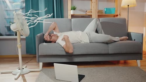 Lazy Man on the Couch with a Laptop Suffers From Hot Weatherheatstroke