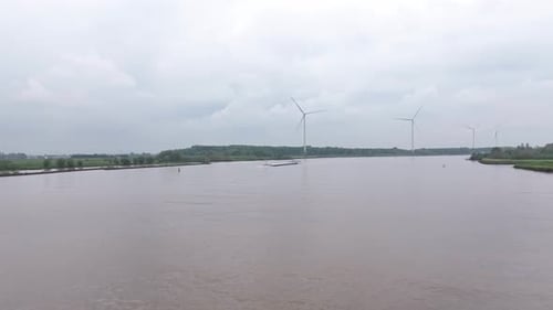 River with Wind Turbines and Barge on Overcast Day