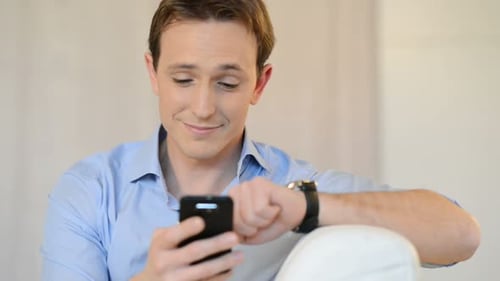 Smiling Man Using Cellphone and Checking Wristwatch