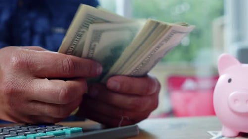 Close Up Male Hands Counting Hundred Dollar Bills In Daylight At Kitchen Table