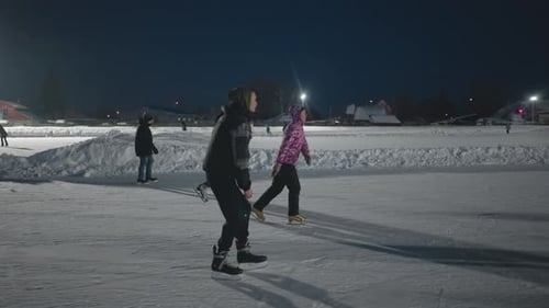 Side View of Young People Skating on Evening Outdoor Ice Rink