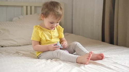 Little Girl Playing with Toys on Bed