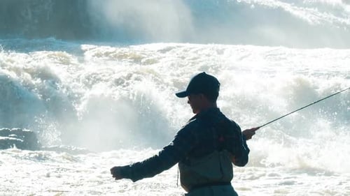 Man Fly Fishing at Base of Rushing Waterfall