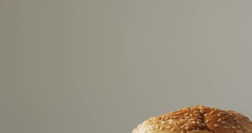 Video close up of cheeseburger with salad in burger bun, on pale grey background with copy space
