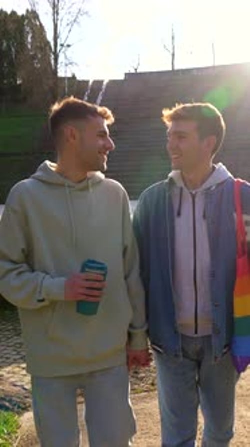 Young caucasian gay couple holding hands and walking in a park