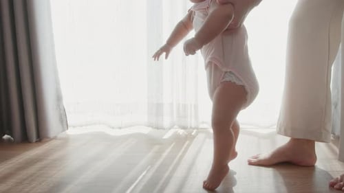 A baby girl learning first steps walk with mother, family, child, childhood and parenthood concept