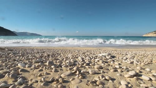 Wellen, die am Kiesstrand mit Wassertropfen krachen