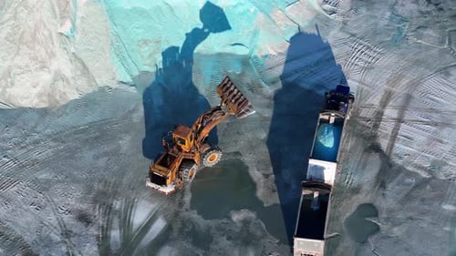 Front loader scooping blue salt into truck at Detroit salt storage site in drone video