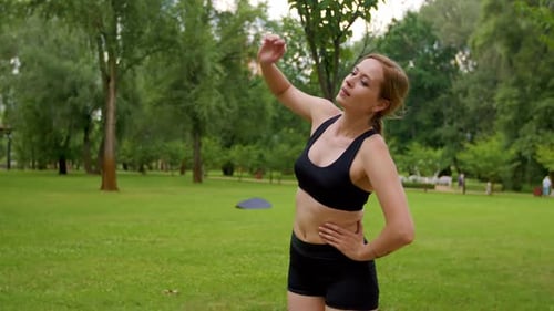Woman Exercises and Stretches in City Park