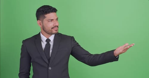 Asian businessman in a black suit showing something or copy space for product or sign text.