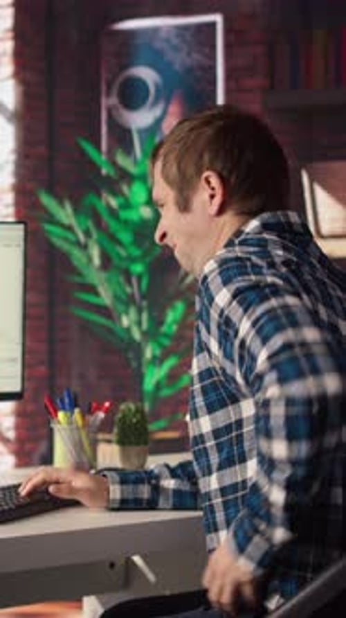 Un homme à la maison s'étire en arrière tout en regardant l'interface utilisateur sur l'écran du PC et se sentant fatigué
