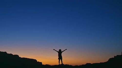 Silhouette einer siegreichen Frau, die auf dem Gipfel eines Berges steht
