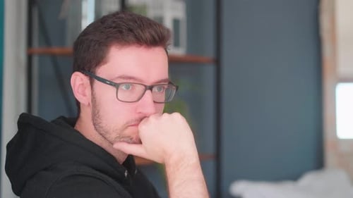 Junger Mann denkt, Hand aufs Kinn, Denken, Pose, Ausdruck, Emotionen, tiefe Gedanken, Nachdenken über PR.