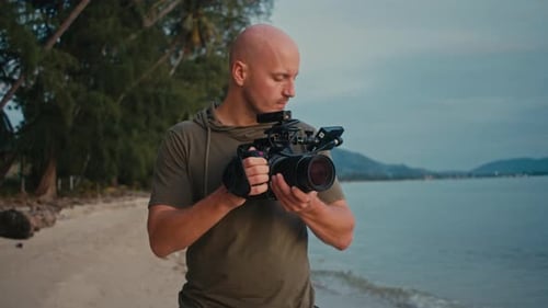 Man Holding Video Camera on Tropical Beach