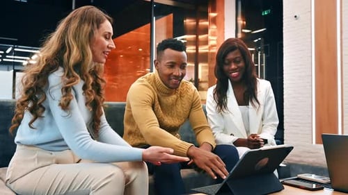 Groupe multiracial de travailleurs d'un bureau discutant affaires à l'aide d'une tablette. Ralenti