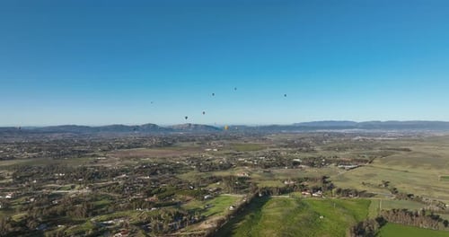 Scenic Aerial View of Balloons Over Rolling Hills