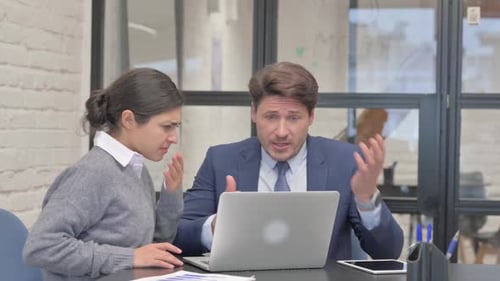 Man and Woman Working Together on Laptop, Looking Worried