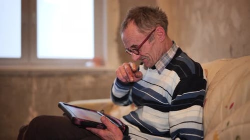 Senior Man Using Tablet Device on Couch