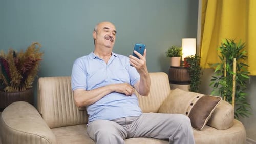 Smiling Man Video Calling on Mobile Phone at Home