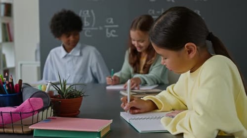 Three Diverse Students Sitting at Classroom Desk in Modern school