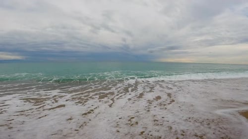 Coarse sand beach sea wave in slow motion at 120fps 4k cloudy day turquoise water single sea waves B