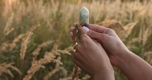 Woman Holds Crystal Healing Point in Field at Sunset