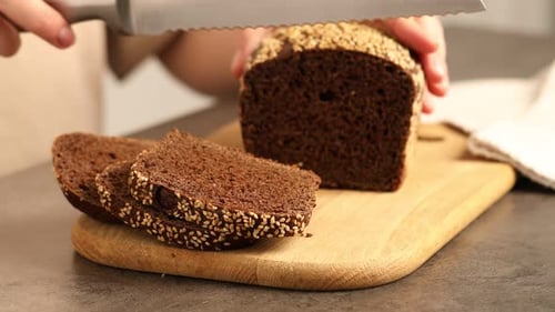 Dark Bread with Sesame Seeds Being Sliced