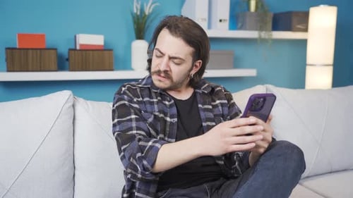 Young Adult Uses Smartphone on Gray Couch