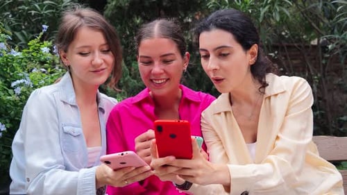 Friends Laughing Looking at Mobile Phones Together