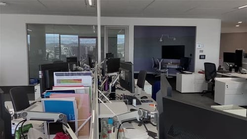 High quality dolly shot over empty desks in a large and deserted office building with unattended wor