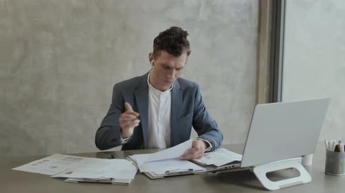 Young Man Working with Laptop and Papers