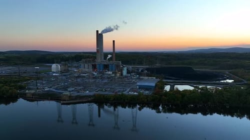 Power plant factory at sunset. Aerial of electricity plant with pile of black coal. Carbon footprint