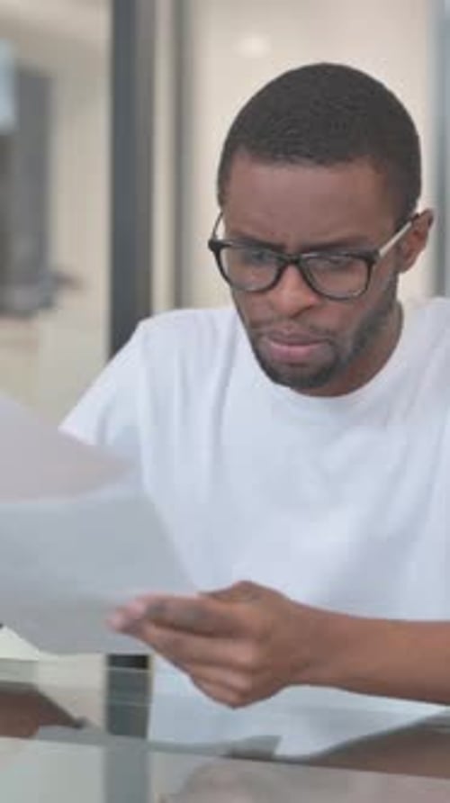 Man Reads Paperwork at a Desk in Office