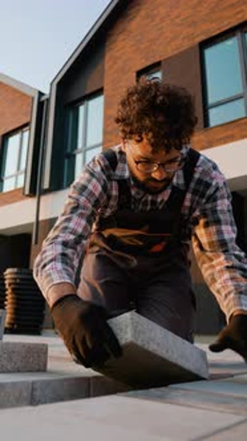 Construction Worker Laying Paving Slabs and Leveling the Surface