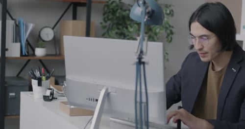 Employé de bureau asiatique utilisant la saisie par ordinateur pointant vers l'écran avec un sourire heureux et réussissant