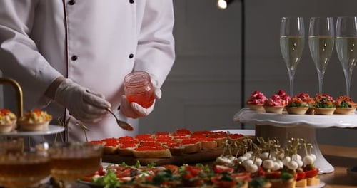 Chef making sandwiches with red caviar for buffet at table indoors, closeup