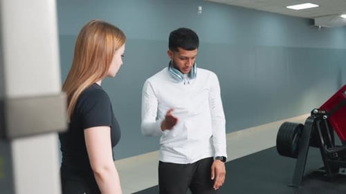 Trainer Guiding Client Through Workout Instruction in Fitness Studio
